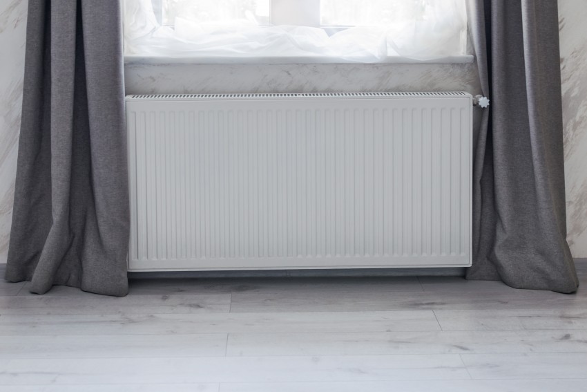 Part of a bright room with heating convector radiator installed under the window.